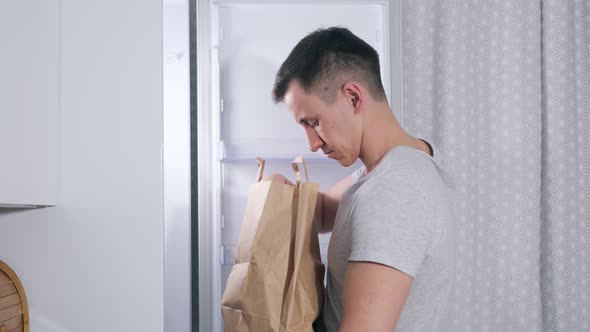Young Man Puts Different Food Products Into Large Fridge