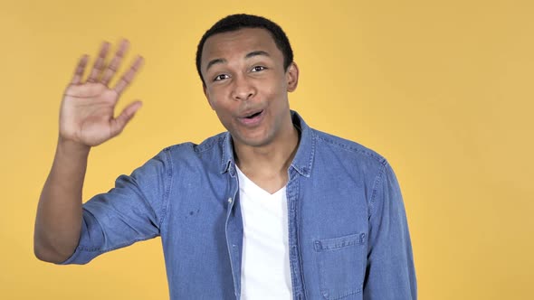 Young African Man Waving Hand to Welcome Yellow Background