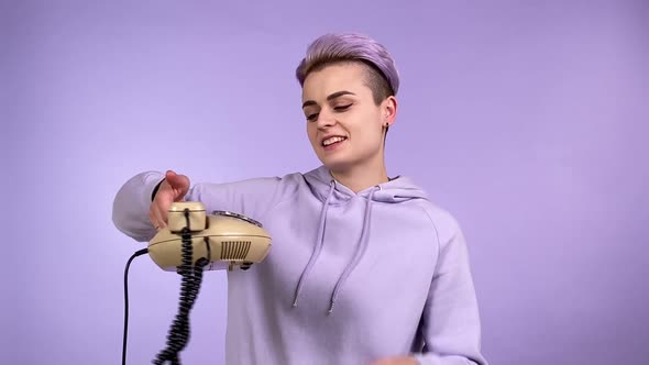 Modern Young Woman Holding Classic Corded Phone Dialing Number Indoors