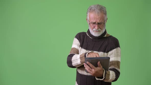 Handsome Senior Bearded Man Wearing Warm Clothing Against Green Background