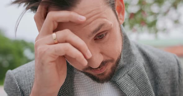 Close Up of Young Mans' Face with Mustaches and a Beard Worried He Touches His Mouth with His Hand