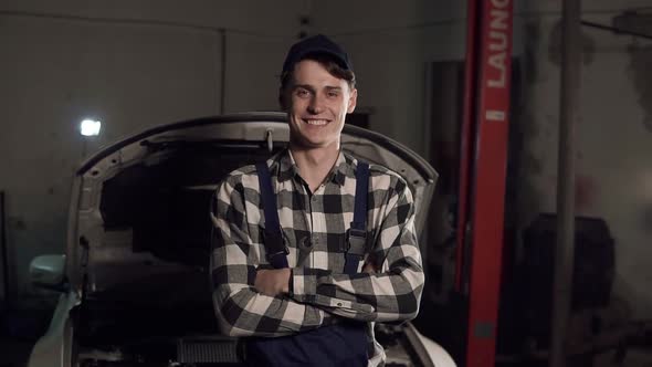 Portrait of Young Handsome Car Mechanic in Workshop in the Background of Service