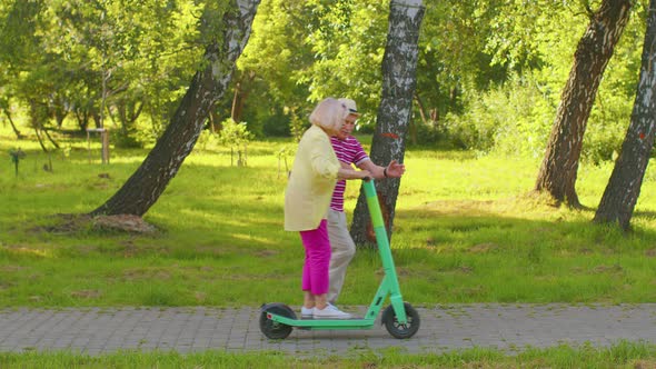 Senior Old Stylish Tourists Grandmother Grandfather Using Electric Scooter While Riding in Park