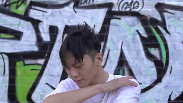 Young Attractive Man Dancing on the Background of Street Graffiti