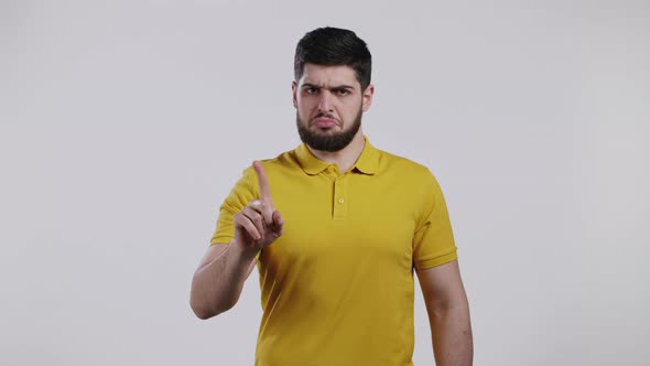 Portrait of Serious Man in Yellow Showing Rejecting Gesture By Stop Finger Sign