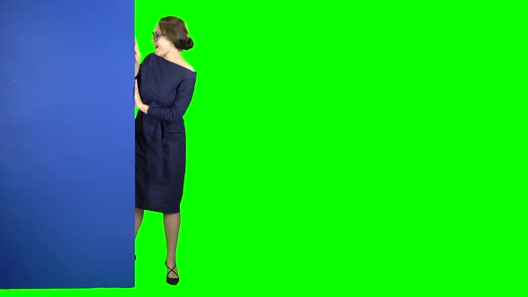 Girl Peeks Out and Points at the Billboard. Green Screen