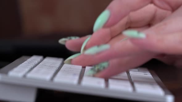 Business Woman's Fingers are Typing on the Keyboard of a White Laptop