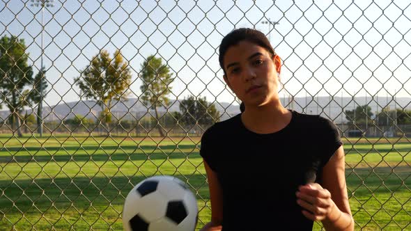 A strong and confident female athlete soccer player holding a football during a competitive sports g