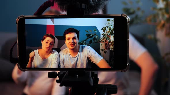 Closeup of Smartphone Standing on a Shoot and Filming an Interview of Young Man and Woman