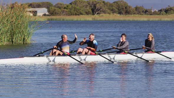 Four senior caucasian men and women in rowing boat high fiving