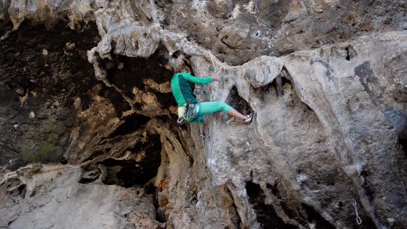 Strong Female Rock Climber Trying to Climb Hard Tough Rock Route on Overhanging Cliff