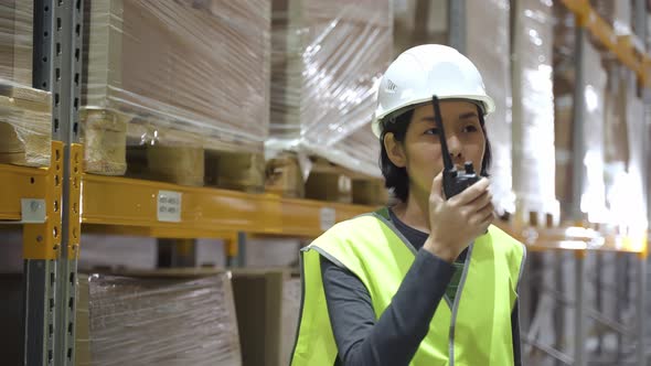 Asian Female Warehouse Worker with Walkie Talkie Talking Discussing on the Radio