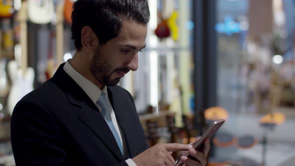 Young handsome business standing sideways and use smartphone