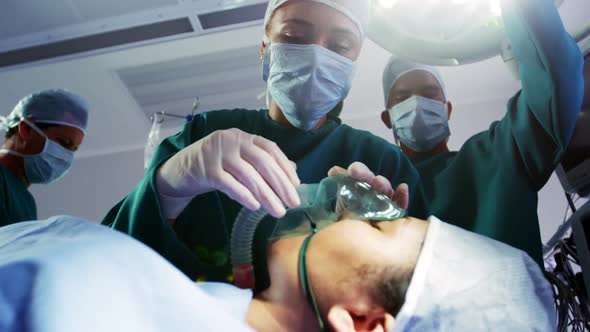 Surgeon putting oxygen mask on patient in operation room