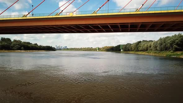 Aerial droneing under the bridges with trafficing over. Going towards city of Warsaw over river 4k