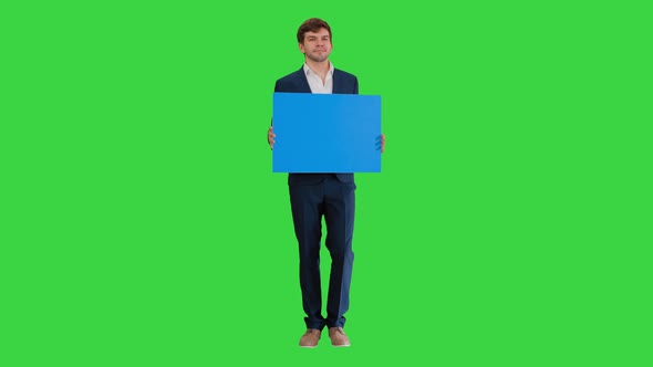 Young Businessman Holding Blank Sign Looking at Camera on a Green Screen, Chroma Key