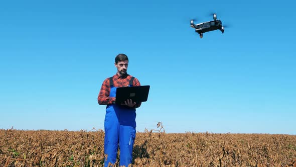 Agronomist Controls a Drone While Standing on a Farmfield