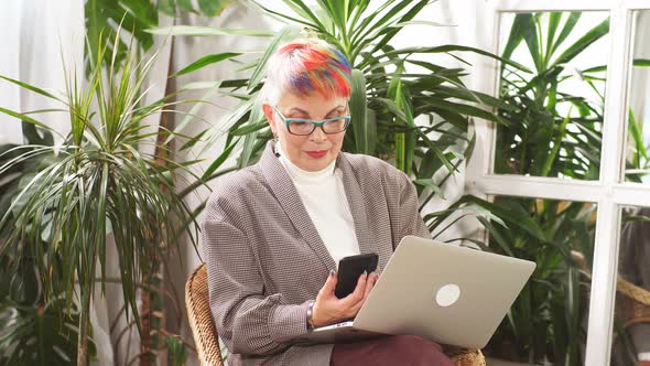 Happy Businesswoman Sitting in Business Center with Laptop and Smartphone