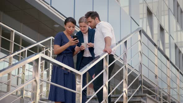 Business Colleagues Discussing Work Issues on Smartphone Outdoor Office Building