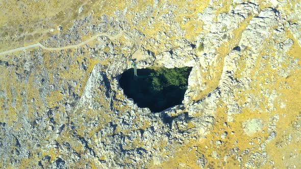 Top View on Sinkhole AkMechet Cave with Trees Inside