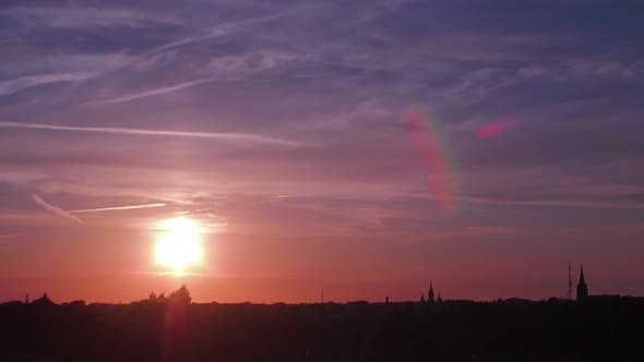 Time lapse of beautiful scenic red sunset over the city with sun shining through the clouds with sun