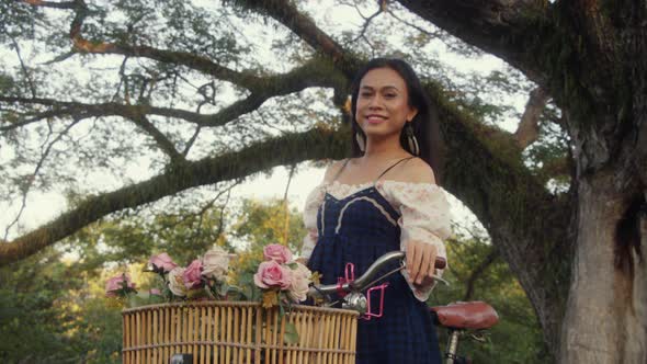 Transgender Asian Woman Standing with Her Bike and Looking at the Camera