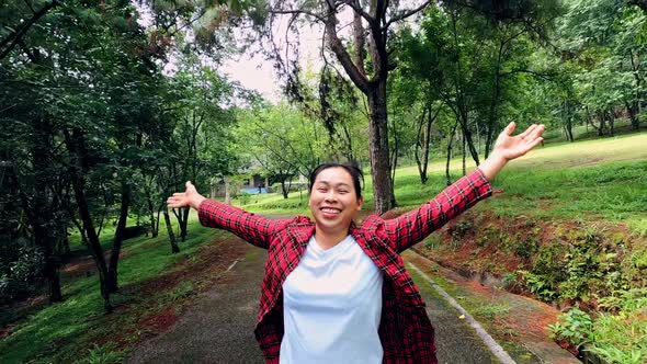 A happy female tourist looking up at the sky with her arms raised enjoying.