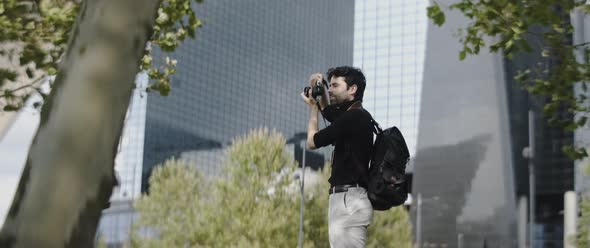 Man taking pictures by large buildings