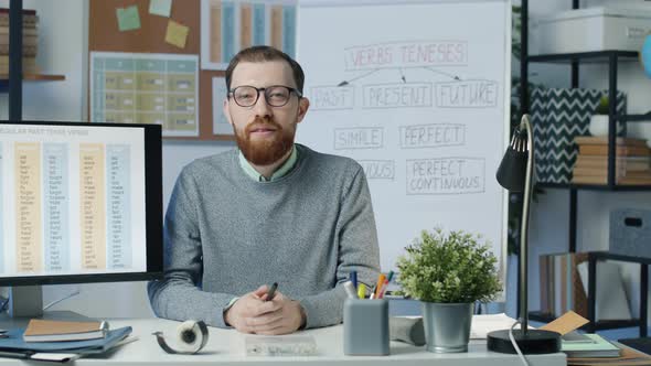 Portrait of School Teacher of English Sitting in Class and Looking at Camera alt