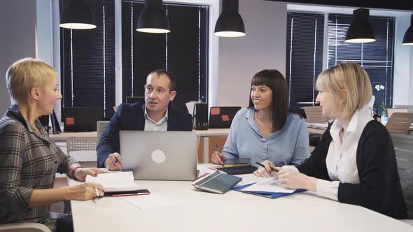 Four Colleagues Discussing New Information and Sitting in Office