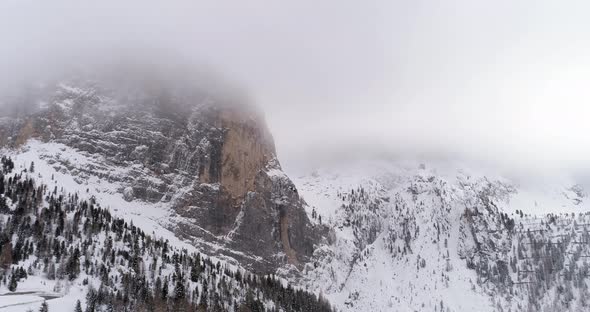 Backward Aerial with Snowy Mountain and Woods Forest at Sella Pass