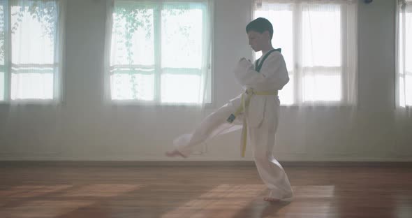 Slow motion footage of a young boy practicing martial arts inside a dojo
