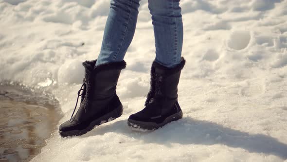 Woman Legs In Winter Boots Breaking Ice. Frozen Lake Ice Cracks And Breaks Under Legs Pressure.