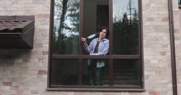 Man Leaned on Window Looks Around Throws Out Mask and Breathes Fresh Air