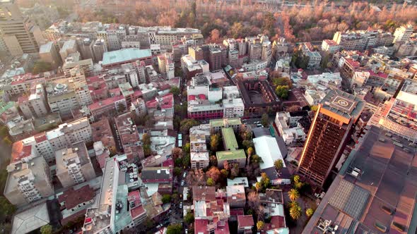 Aerial dolly in of Lastarria neighborhood buildings and Forestal Park autumnal trees in background a