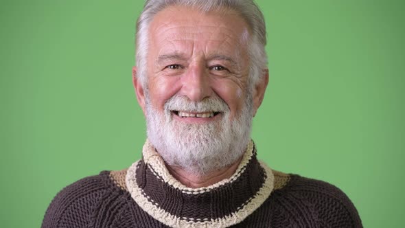 Handsome Senior Bearded Man Wearing Warm Clothing Against Green Background