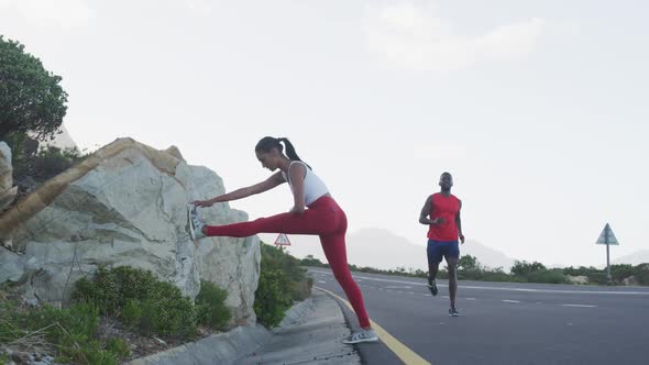 Diverse fit couple exercising stretching and running on a country road