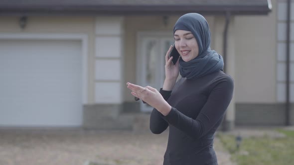 Young Smiling Eastern Woman in Balck Clothes and Beautiful Headdress Talking By Cellphone Holding