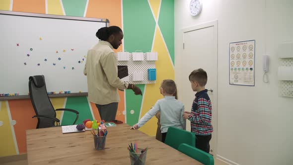 An African American Teacher and a Group of Children are Studying Fruits and Animals in the Classroom