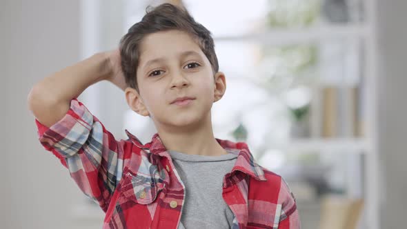 Portrait of Cute Middle Eastern Boy with Big Brown Eyes Adjusting Hair and Moving Brows