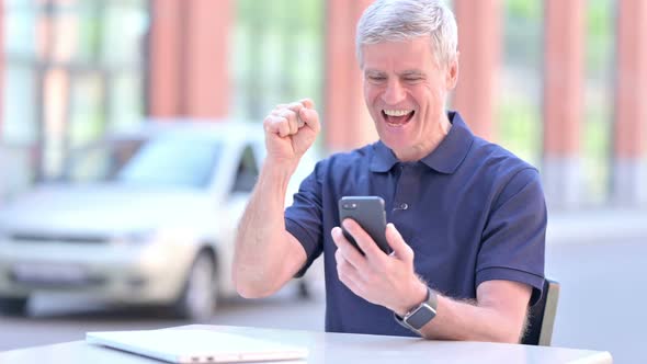 Outdoor Successful Middle Aged Businessman Celebrating on Smartphone