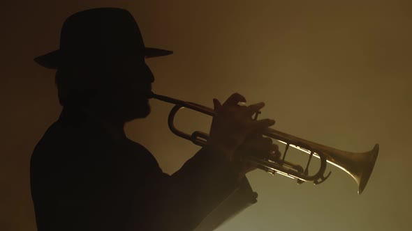 Jazz Musician in Suit and Hat Plays Trumpet in Fog Lit By Lantern Front View