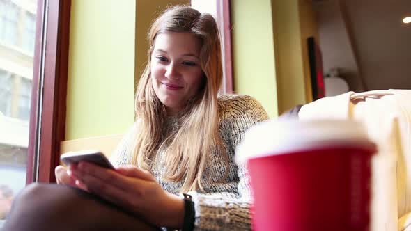 Woman in a London cafe looking at smart phone