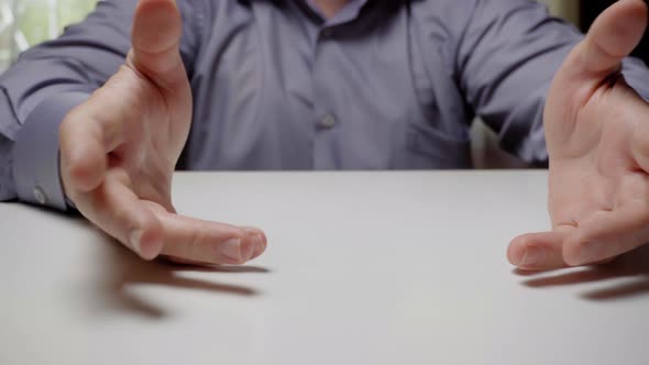 Clerk or businessman spread his arms while sitting at the table, close-up