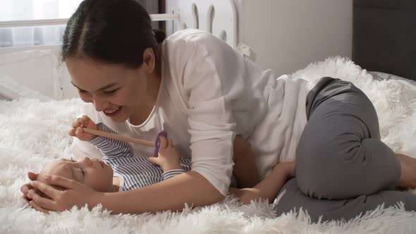 Affectionate Asian Mom Stroking and Kissing Baby