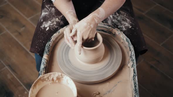 Man Potter Working on Potters Wheel Making Ceramic Pot From Clay in Pottery Workshop