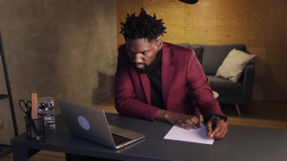 Black Business Man Working on Laptop and Taking Notes