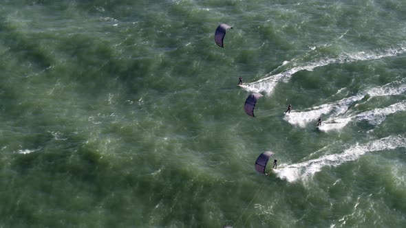 Awesome scene of four kitesurfers moving together over open ocean; aerial