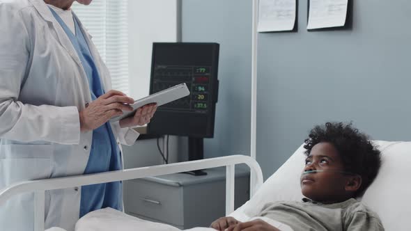 Female Doctor Talking to Boy in Hospital Ward