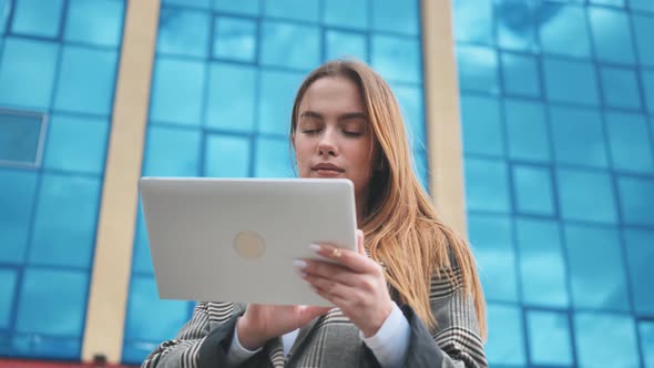 A Young Girl Student Works with a White Tablet in the City